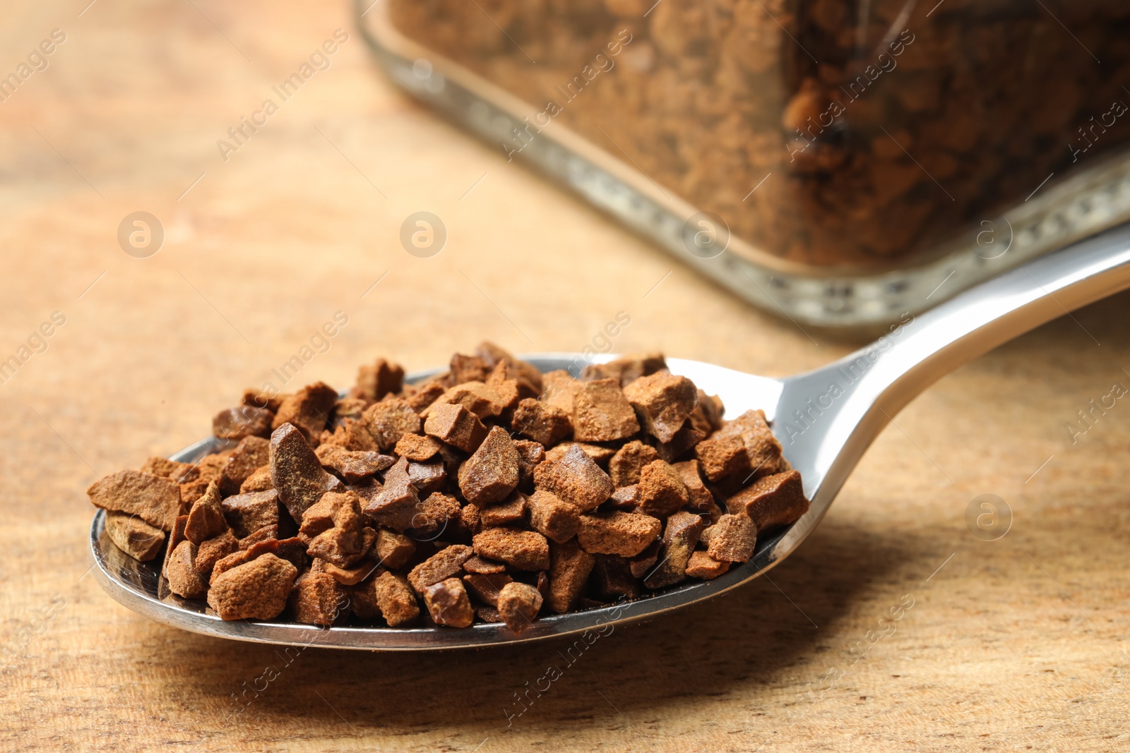 Photo of Spoon of chicory granules on wooden table, closeup