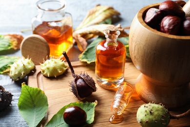 Horse chestnuts, leaves and bottles of tincture on grey table