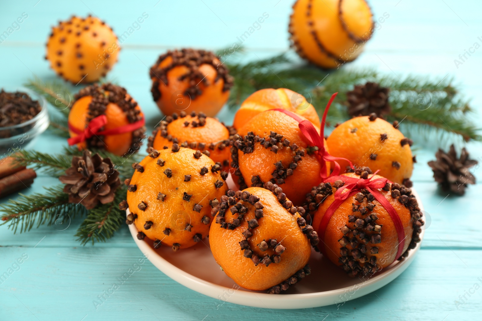 Photo of Pomander balls made of fresh tangerines and cloves on light blue wooden table