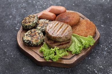 Photo of Different tasty vegan meat products on grey table