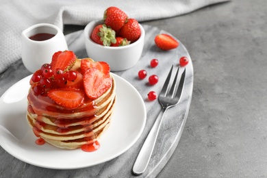 Tasty pancakes with berries served on grey table