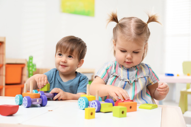 Photo of Little children playing with construction set at table