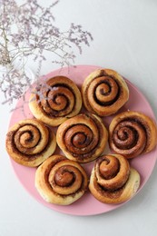 Many tasty cinnamon rolls on white table, top view