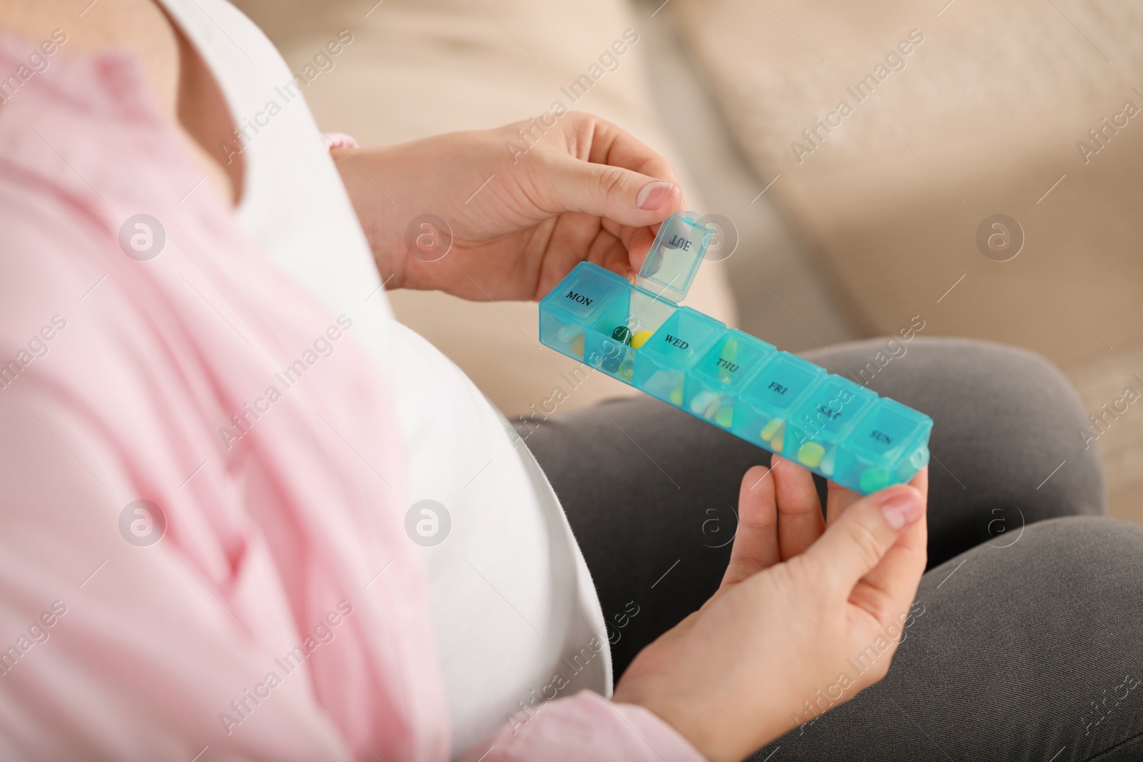 Photo of Pregnant woman holding box with pills on blurred background, closeup