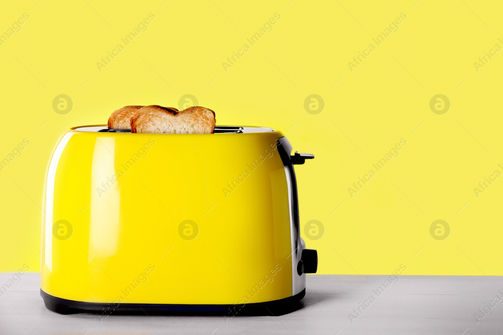 Photo of Modern toaster with slices of roasted bread on white wooden table. Space for text