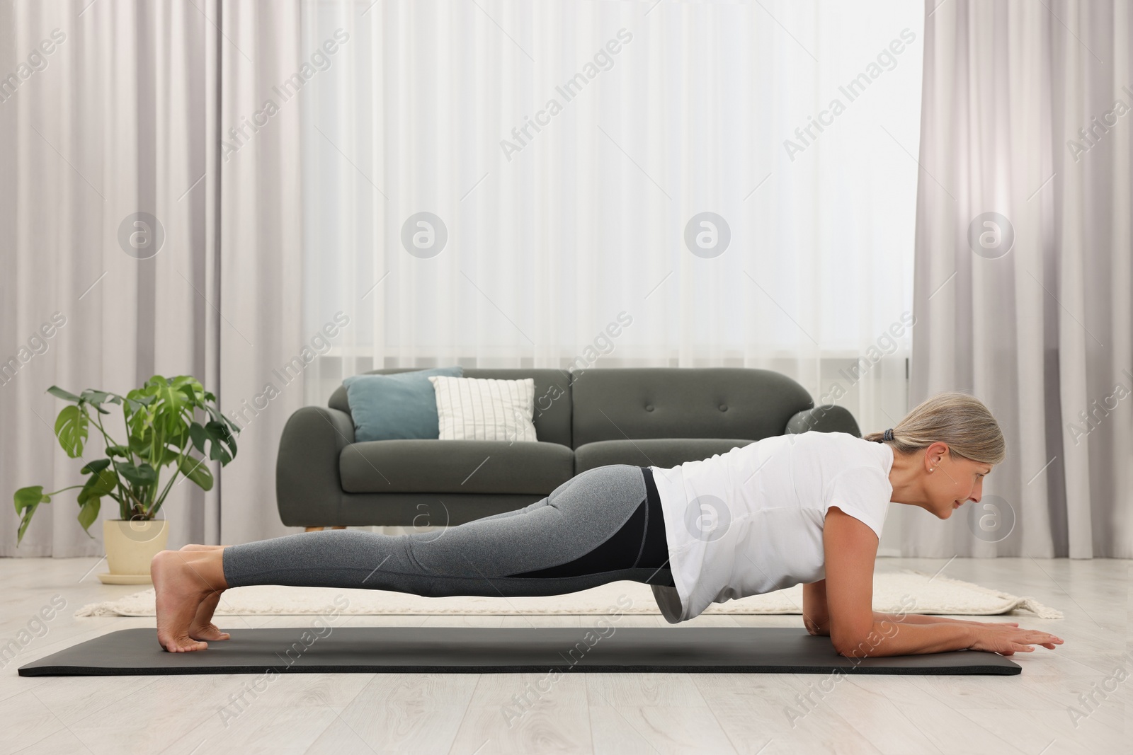 Photo of Senior woman practicing yoga on mat at home