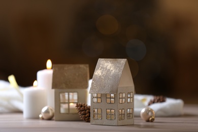 Composition with house shaped candle holder on wooden table against blurred background, space for text. Christmas decoration