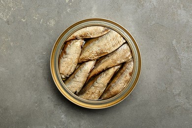Photo of Sprats in tin can on grey textured table, top view