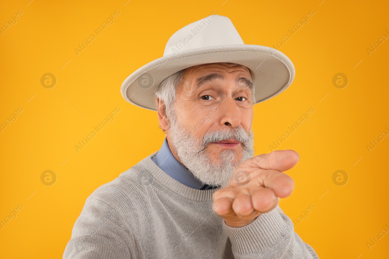 Photo of Senior man blowing kiss on yellow background