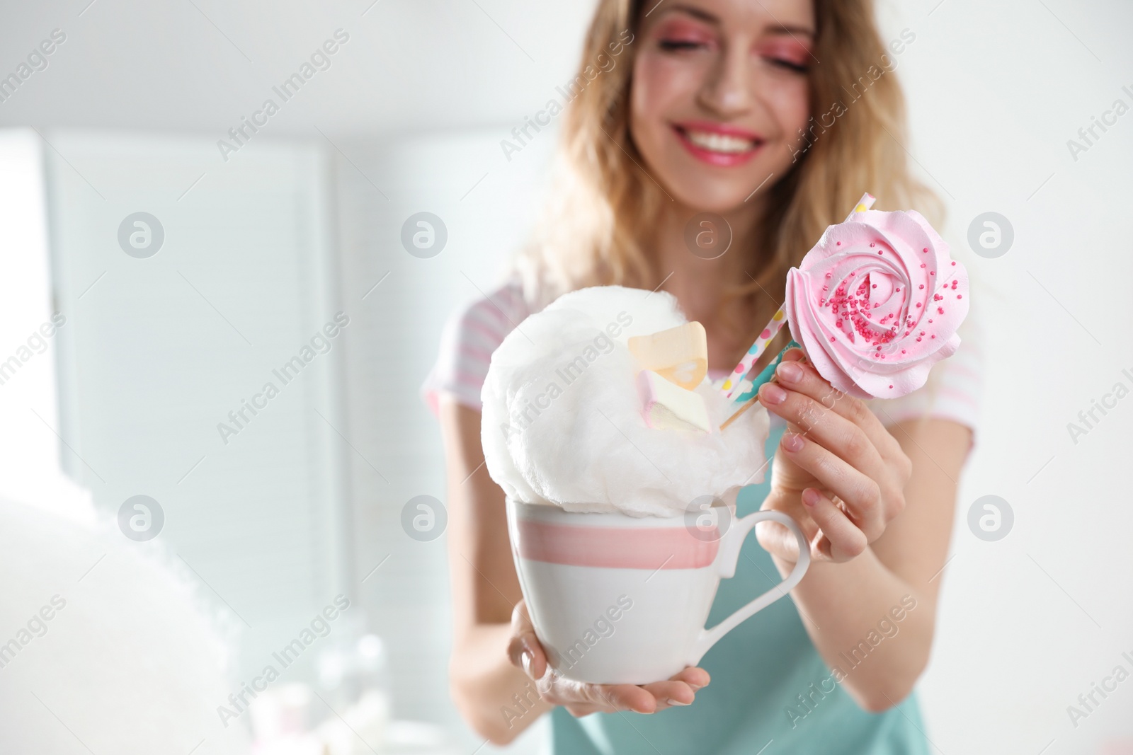 Photo of Young woman with cup of cotton candy dessert indoors, closeup. Space for text