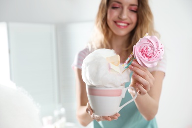 Young woman with cup of cotton candy dessert indoors, closeup. Space for text