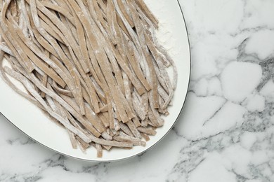 Uncooked homemade soba (buckwheat noodles) on white marble table, top view