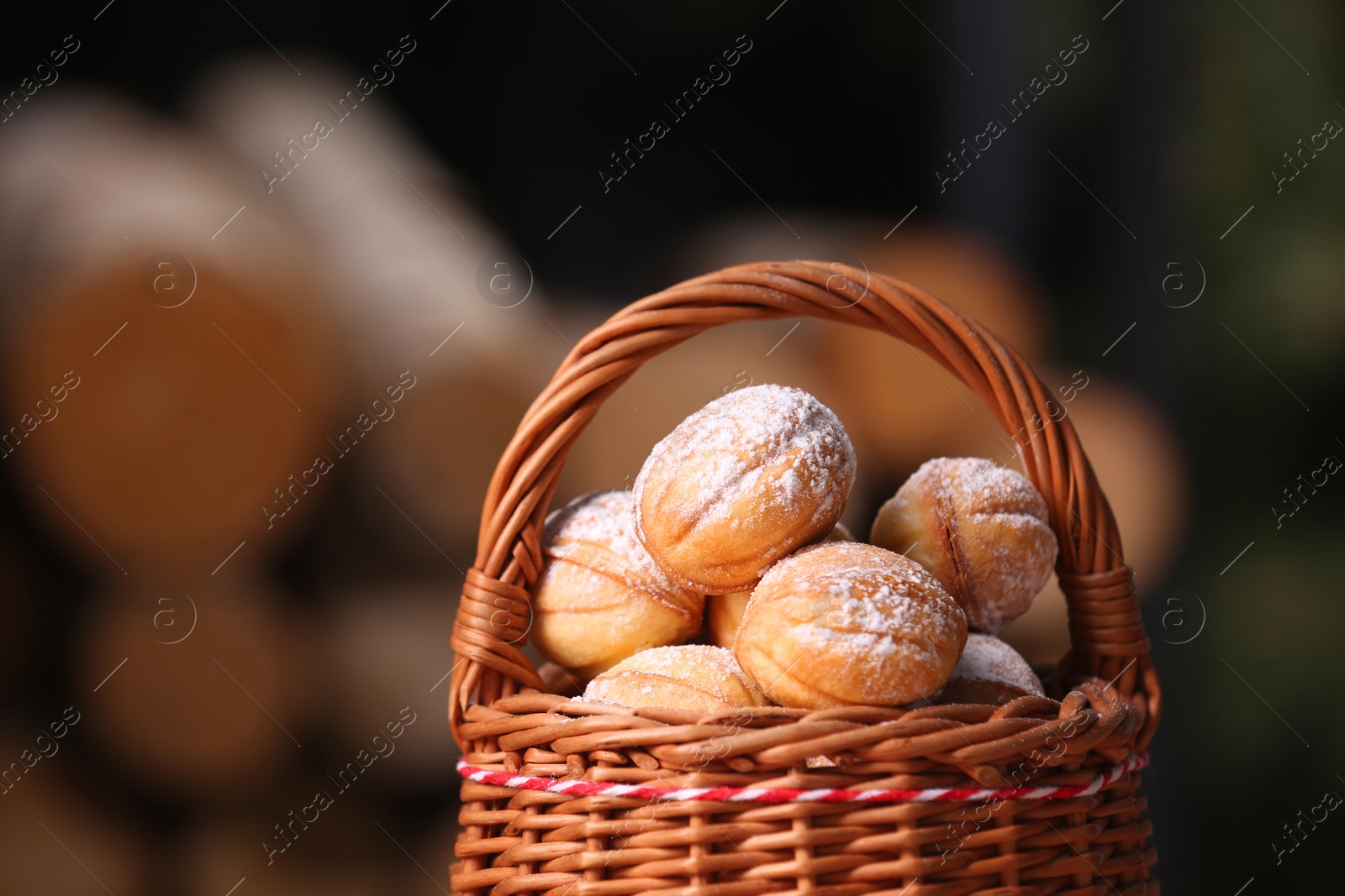 Photo of Wicker basket with delicious nut shaped cookies on blurred background, closeup. Space for text