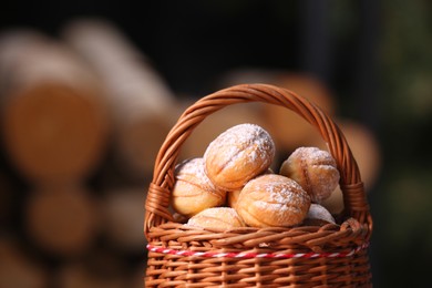 Wicker basket with delicious nut shaped cookies on blurred background, closeup. Space for text