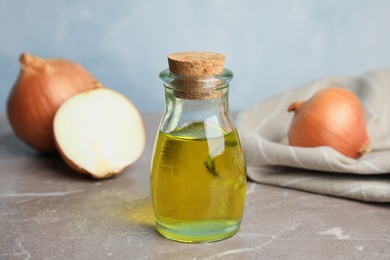 Photo of Glass bottle of onion syrup and fresh vegetable on table