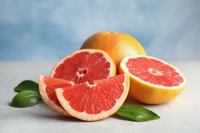 Photo of Fresh tasty grapefruits on table against color background