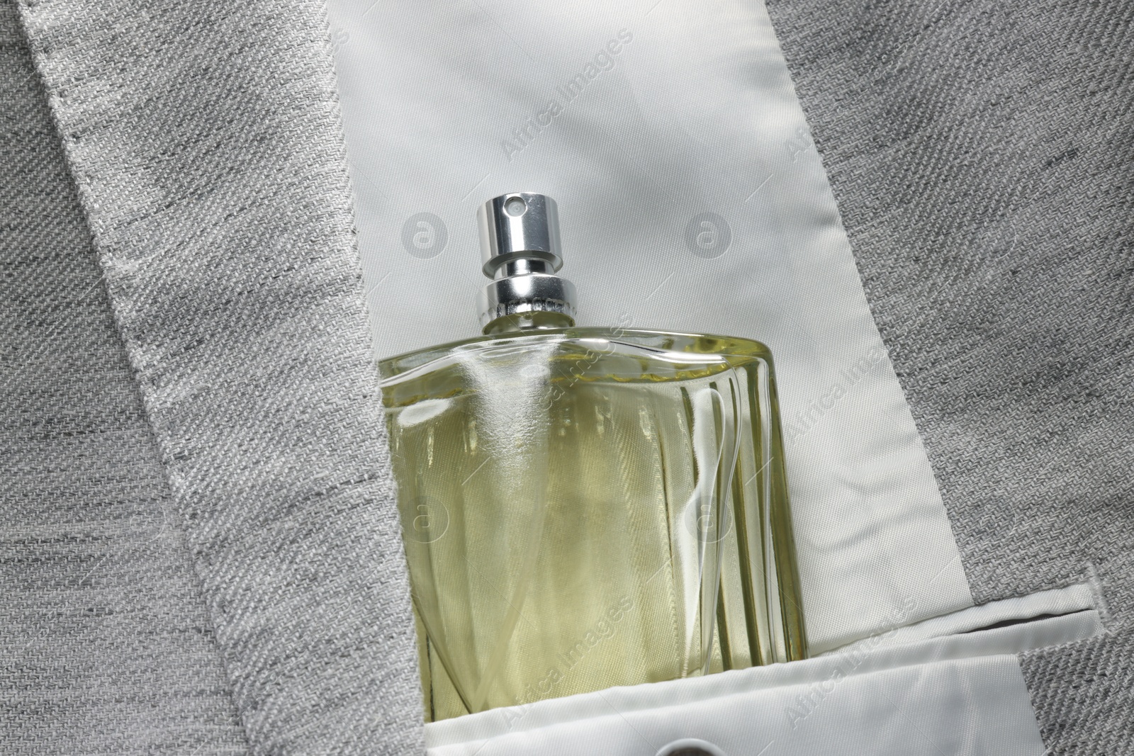 Photo of Luxury men's perfume in inner pocket of grey jacket, top view