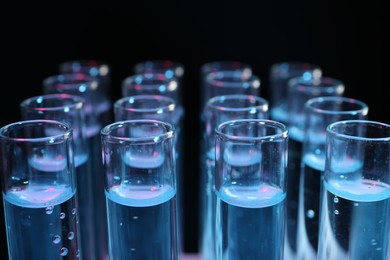 Photo of Test tubes with liquid on black background, closeup. Laboratory analysis