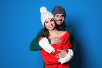 Young couple in warm clothes on color background. Christmas celebration