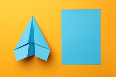 Photo of Handmade light blue plane and piece of paper on yellow background, flat lay