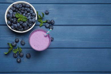 Photo of Glass of blueberry smoothie with mint and fresh berries on blue wooden table, flat lay. Space for text
