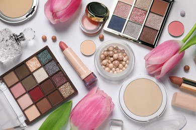 Photo of Flat lay composition with eyeshadow palettes and beautiful flowers on white background