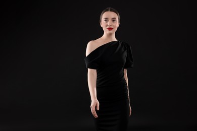 Beautiful young woman in elegant dress on black background