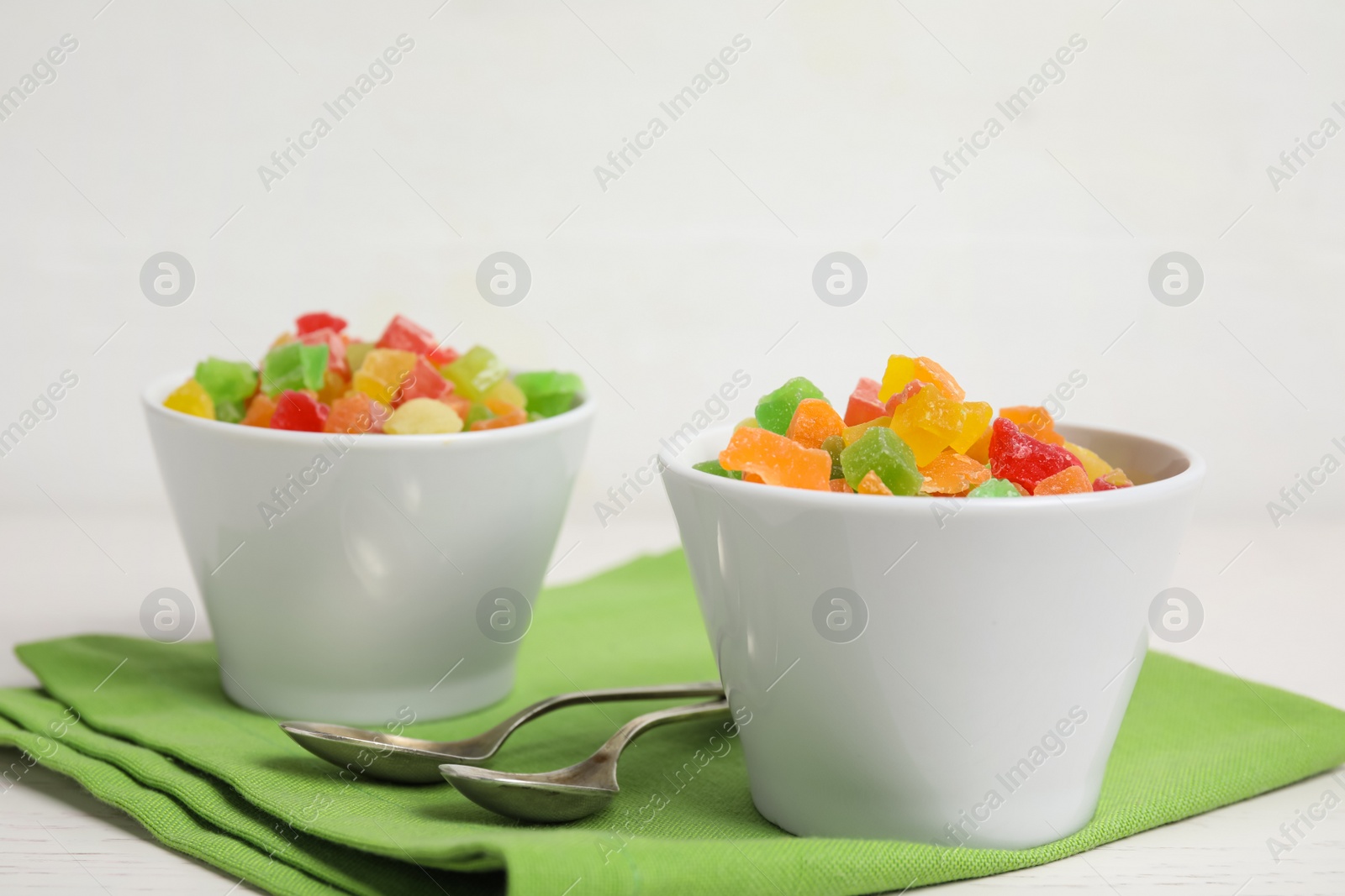 Photo of Spoons and bowls with delicious candied fruits on table