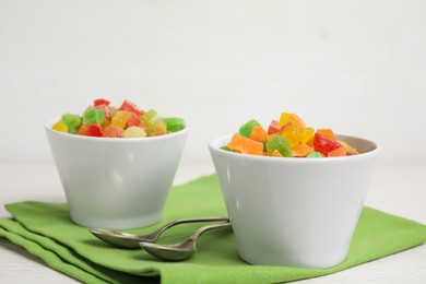 Spoons and bowls with delicious candied fruits on table