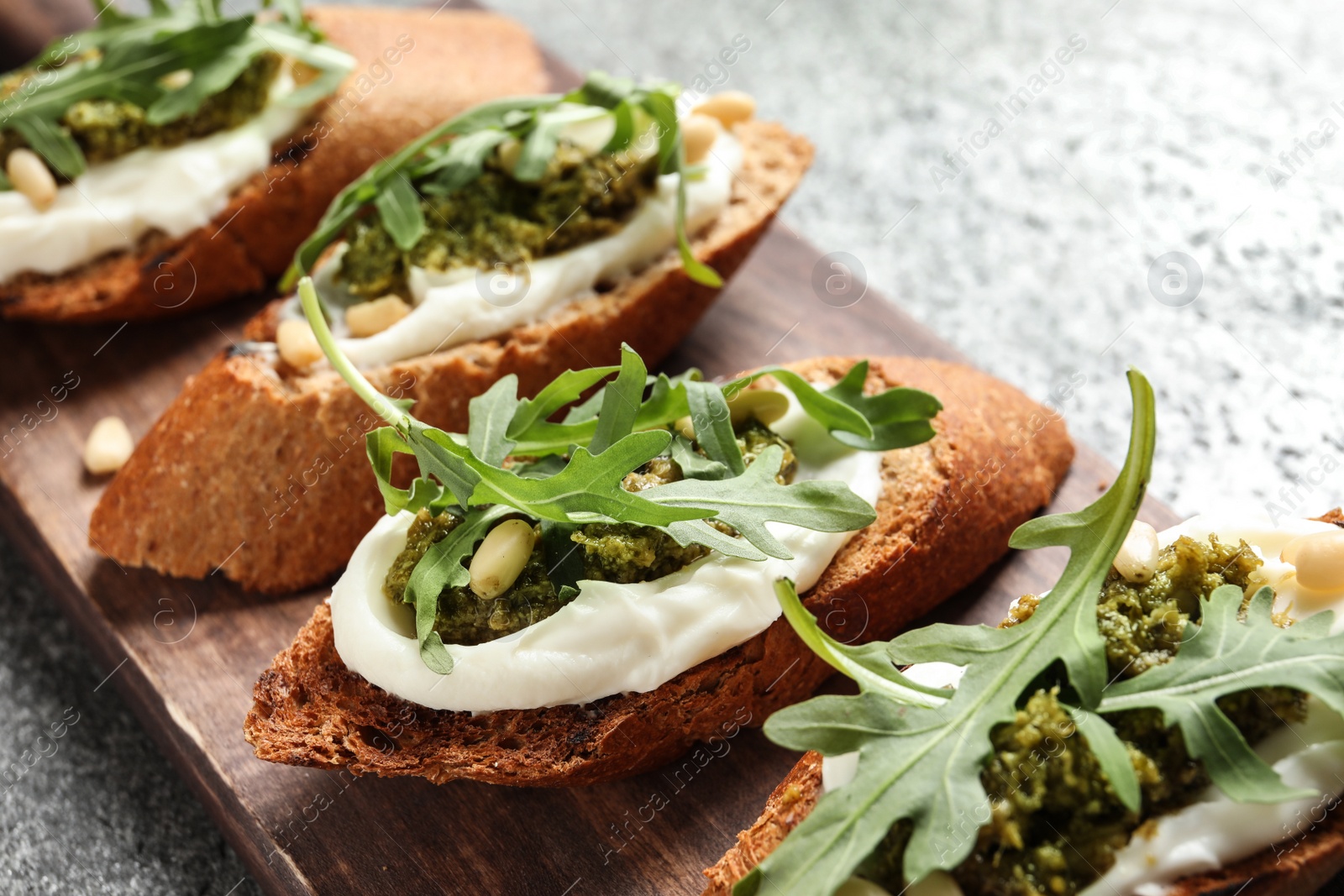 Photo of Serving board with tasty bruschettas on grey table, closeup