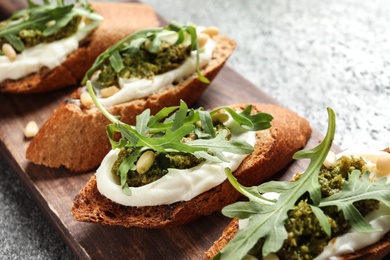 Photo of Serving board with tasty bruschettas on grey table, closeup