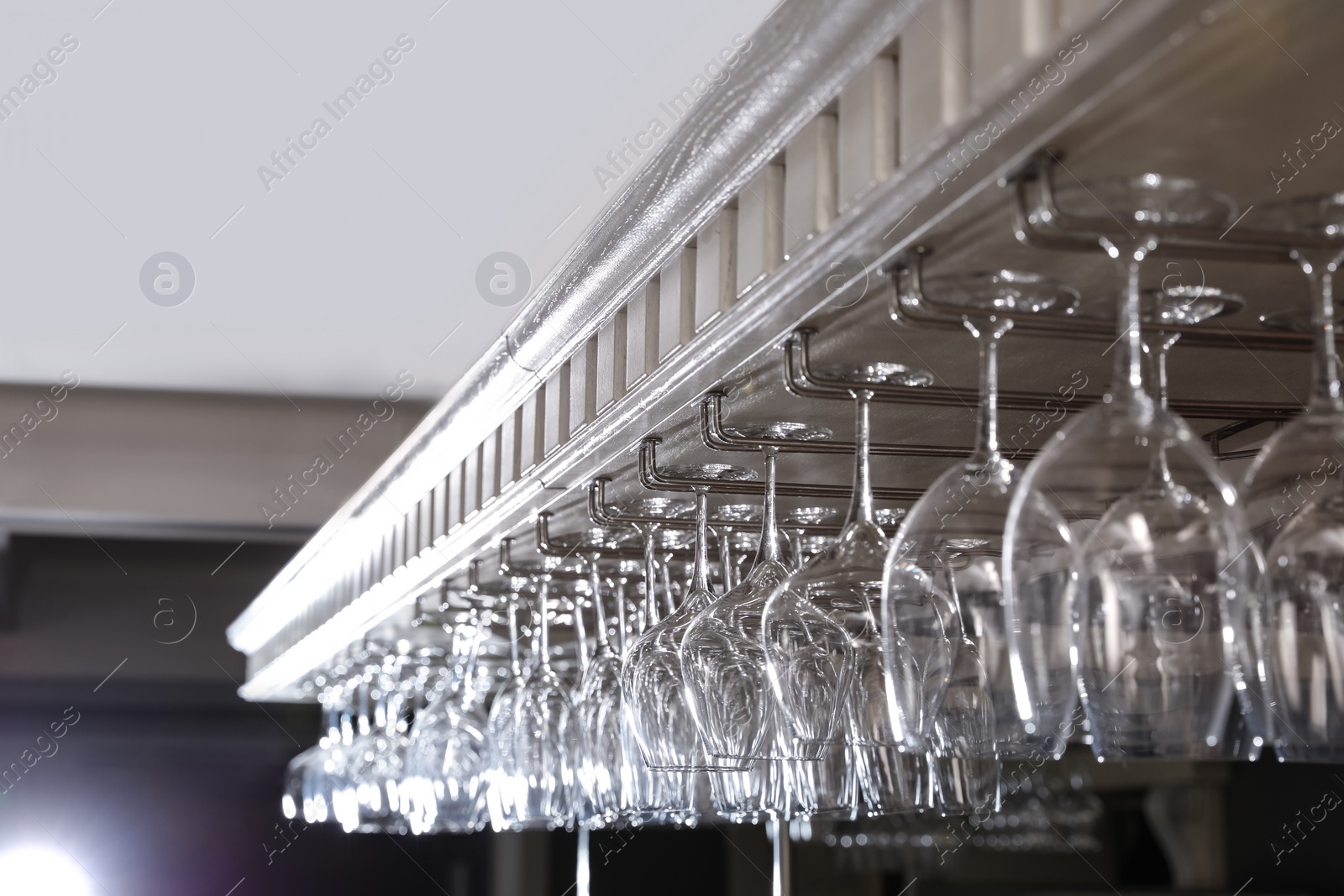 Photo of Set of empty clean glasses on bar racks