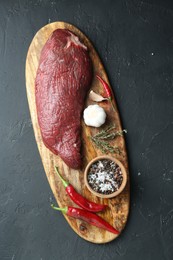 Piece of raw beef meat, products and spices on dark textured table, top view
