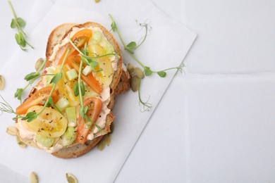 Photo of Tasty vegan sandwich with tomatoes, celery and microgreens on white tiled table, top view. Space for text