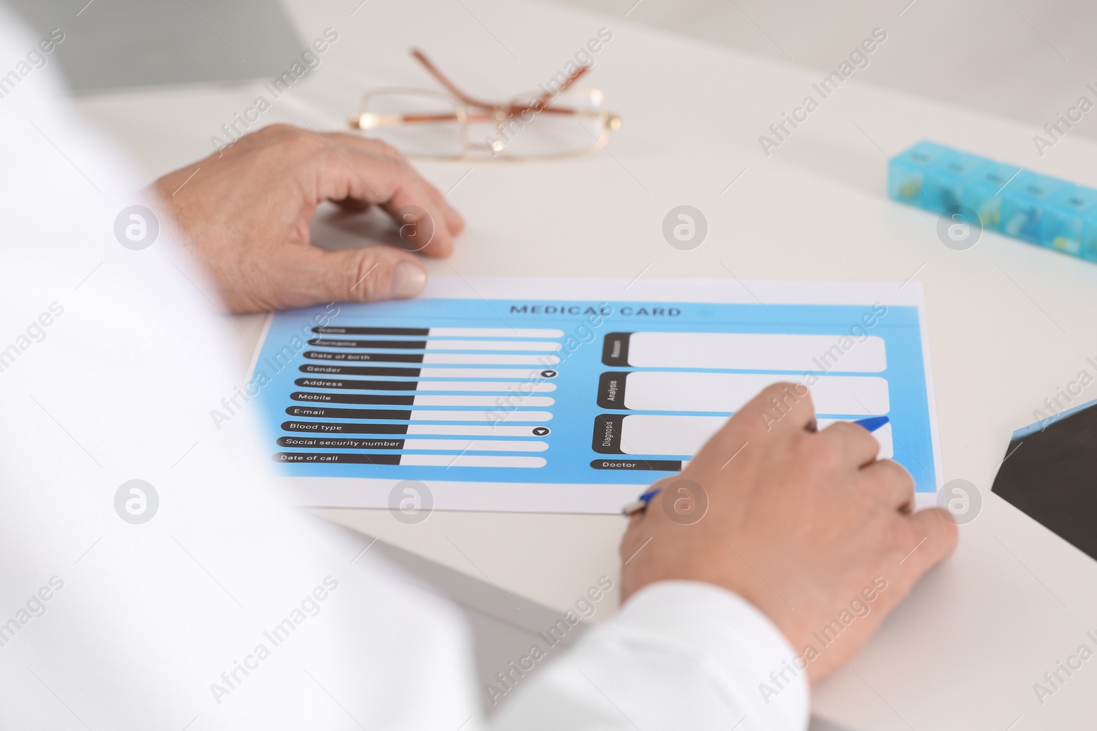 Photo of Doctor with patient's medical card at table in clinic, closeup