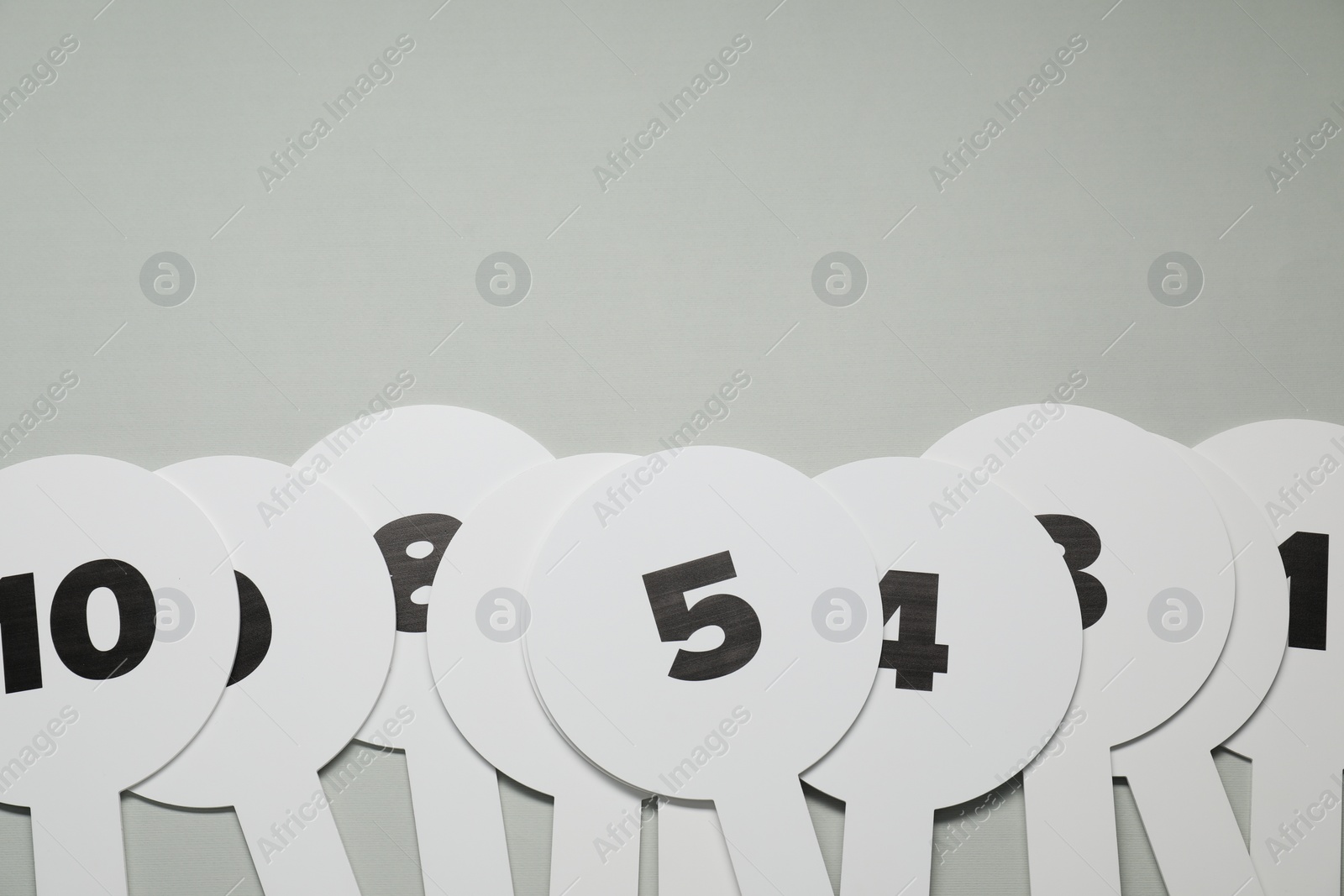 Photo of Auction paddles with numbers on light grey background, flat lay. Space for text