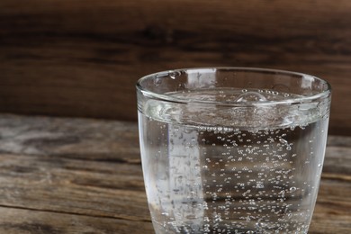 Photo of Glass of soda water on wooden background, closeup. Space for text