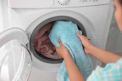 Photo of Woman putting dirty laundry into washing machine indoors, closeup