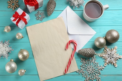 Photo of Flat lay composition with blank sheet of paper and Christmas decorations on turquoise wooden table, space for text. Writing letter to Santa