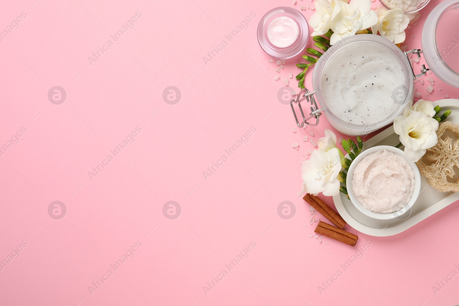 Photo of Flat lay composition with body scrubs on pink background, space for text