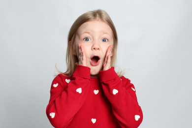 Portrait of cute emotional little girl on light grey background