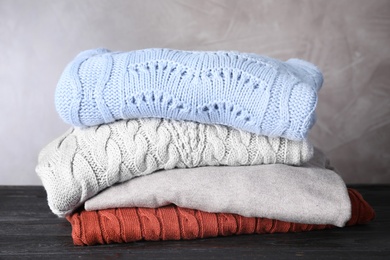 Image of Stack of folded warm sweaters on black wooden table 