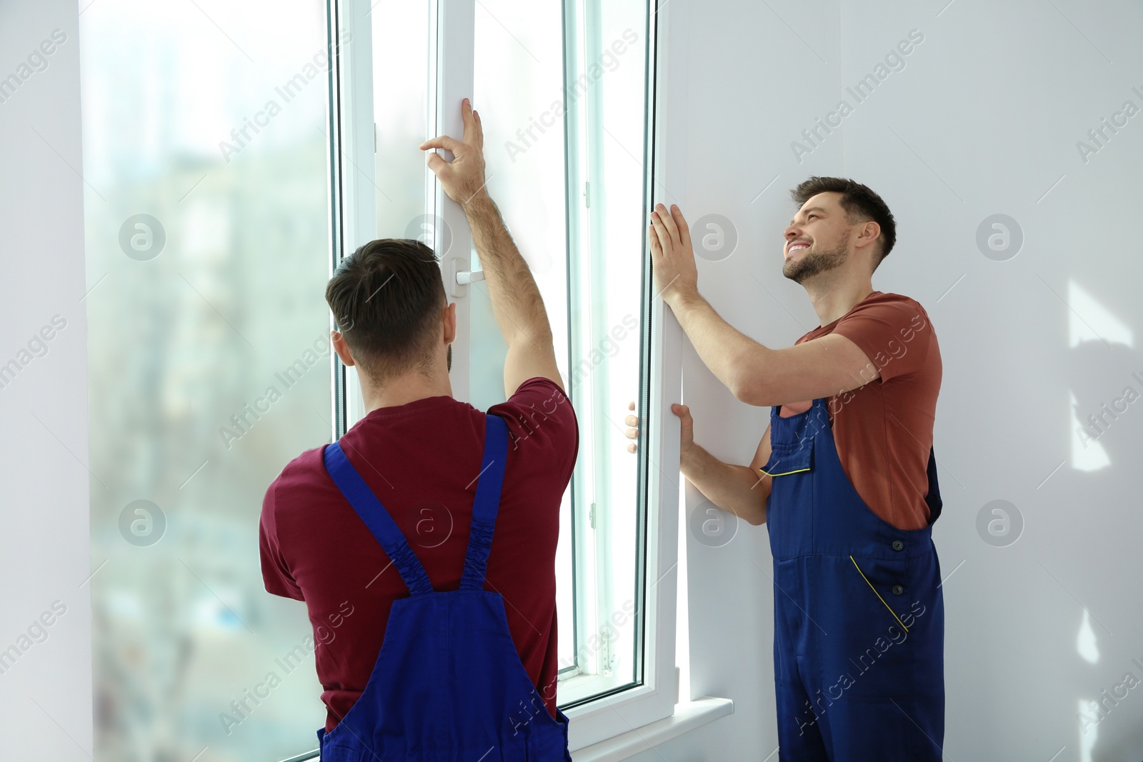 Photo of Construction workers installing plastic window in house