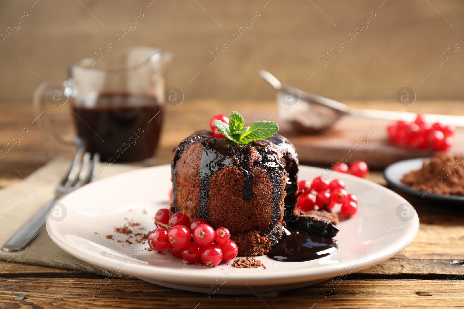 Photo of Delicious warm chocolate lava cake with mint and berries on wooden table