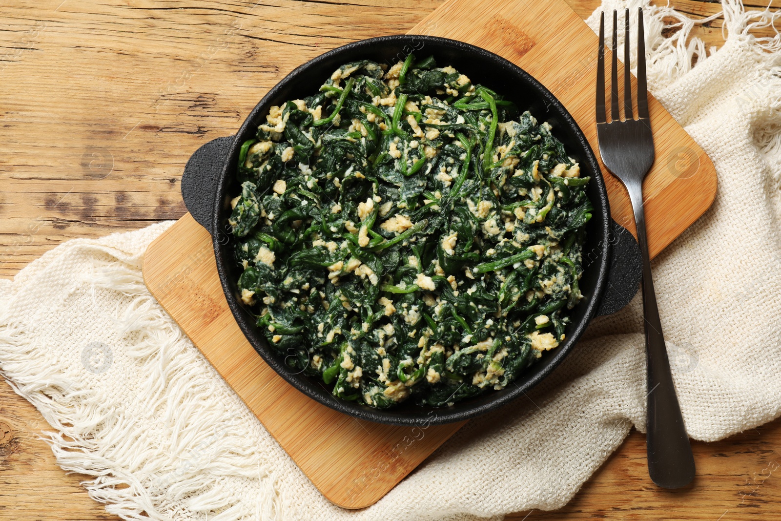 Photo of Tasty spinach dip with eggs in dish served on wooden table, top view