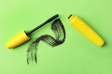 Photo of Mascara for eyelashes and smear on green background, flat lay. Makeup product