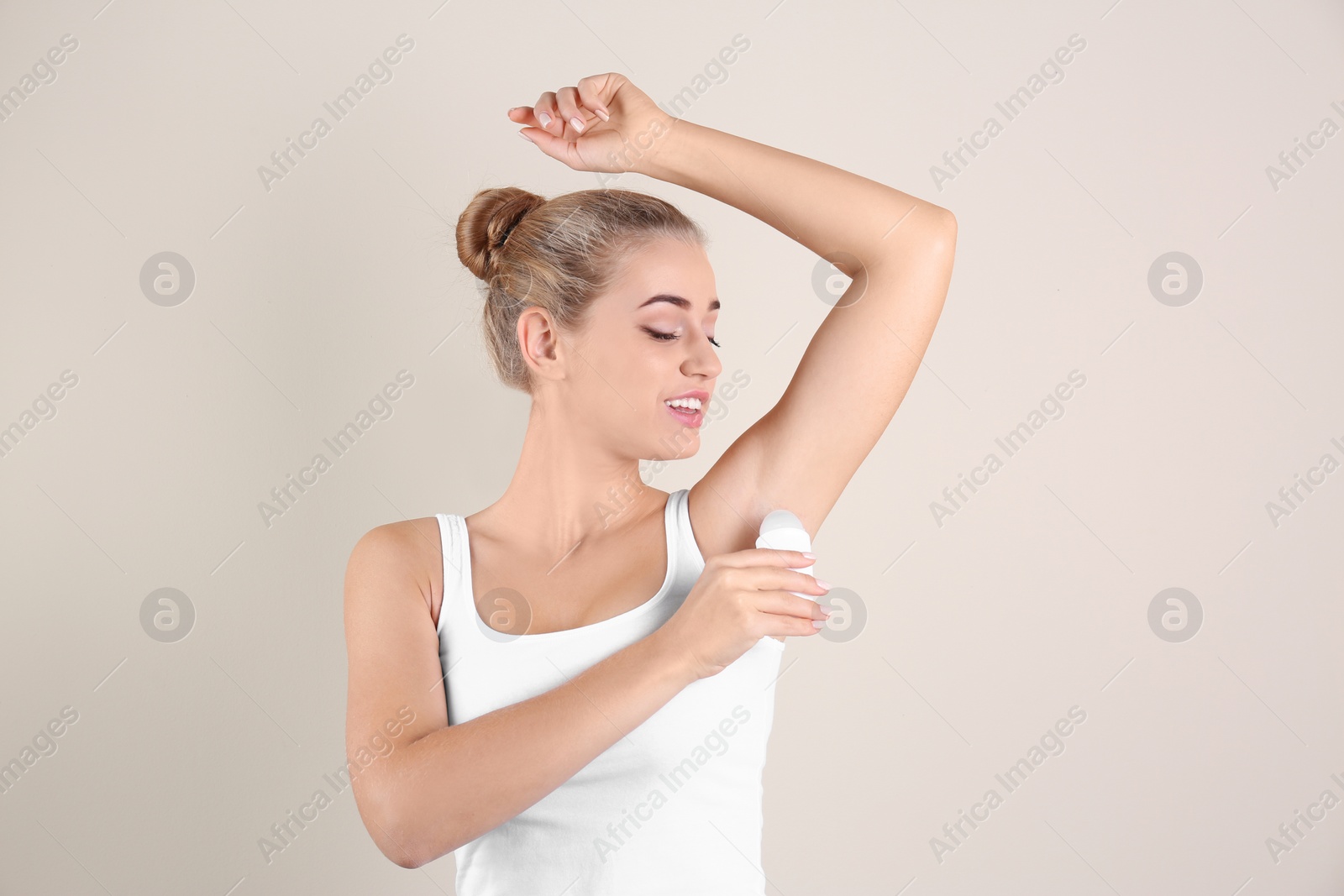 Photo of Young woman using deodorant on color background