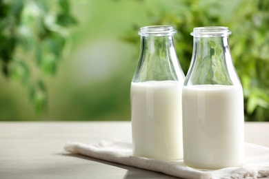 Photo of Fresh milk on wooden table against blurred background, space for text