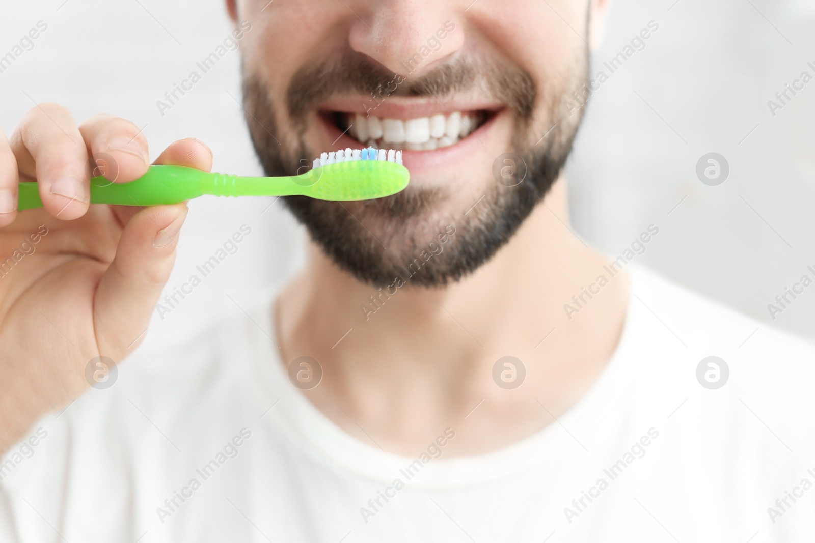 Photo of Young man brushing his teeth indoors