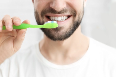 Photo of Young man brushing his teeth indoors